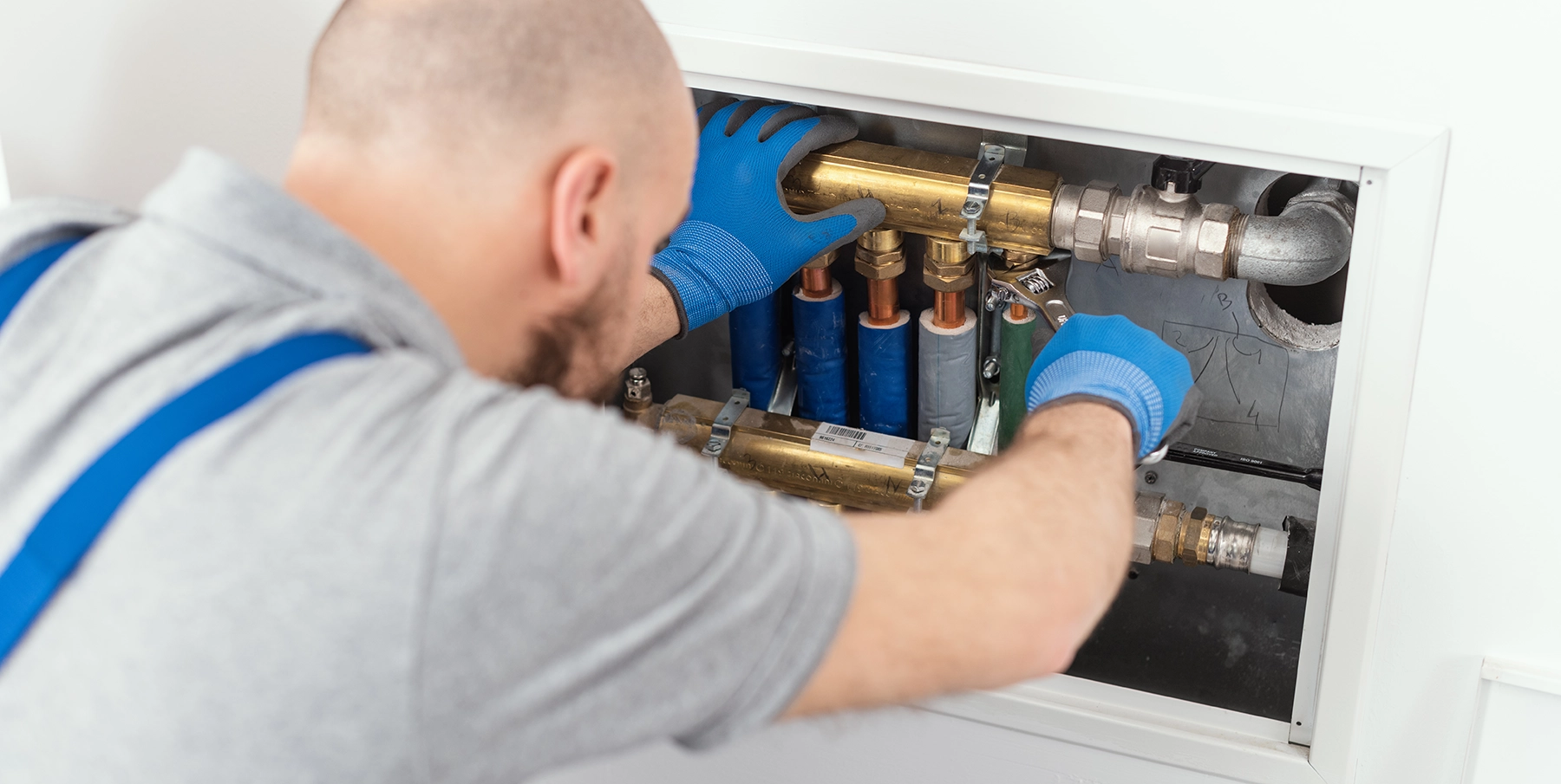A man performs plumbing maintenance on a piping system.